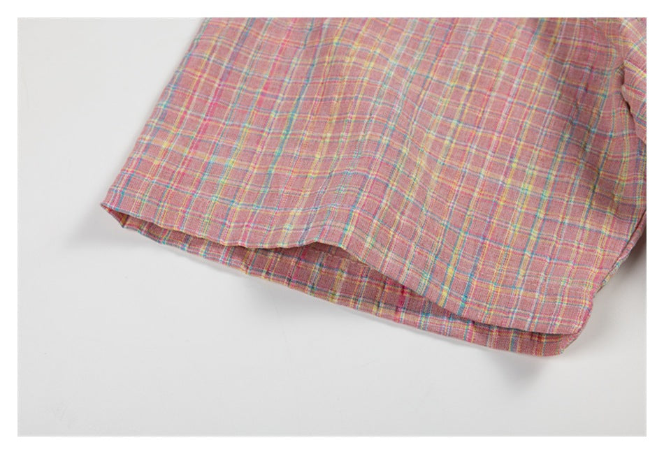 Close-up of the curved hem of a pink plaid shirt with fine teal and yellow stripes.
