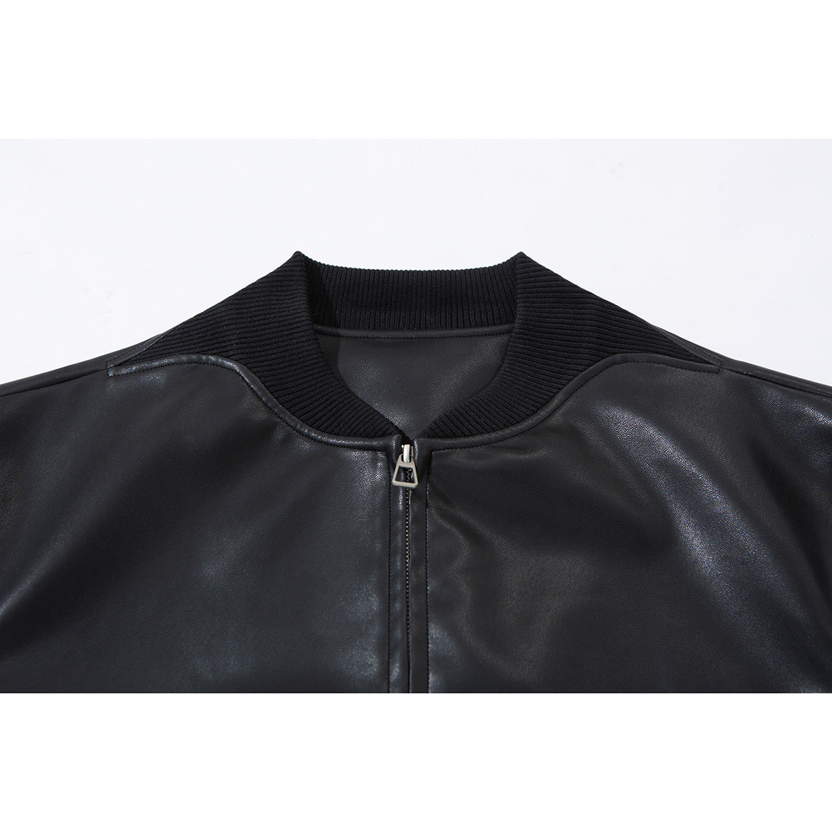 Close-up of a black jacket’s ribbed collar, front zipper, and glossy shoulder panels.