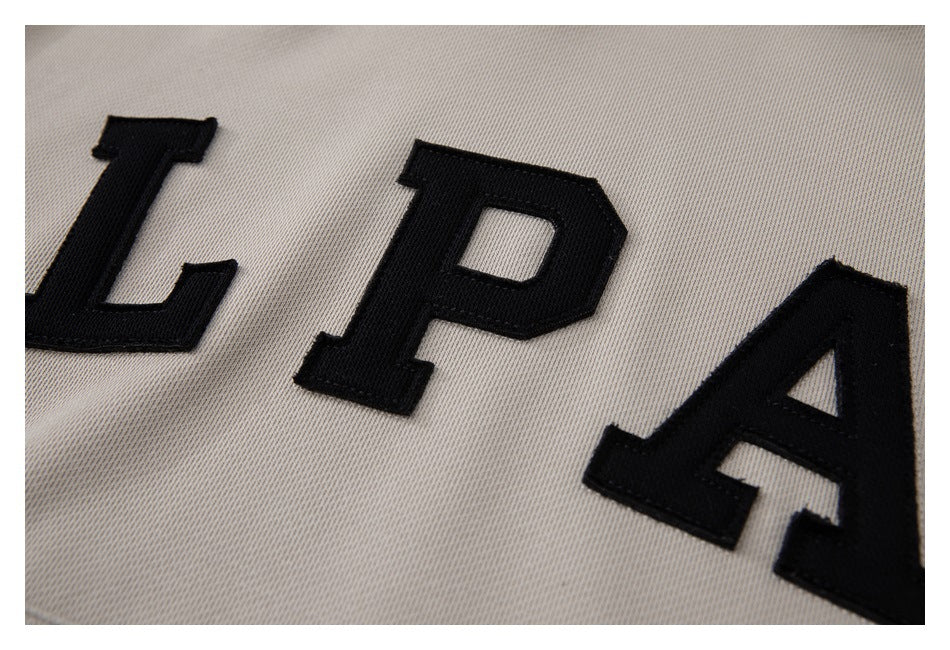 Close-up of raised black LPA letters appliquéd on the taupe sweatshirt.