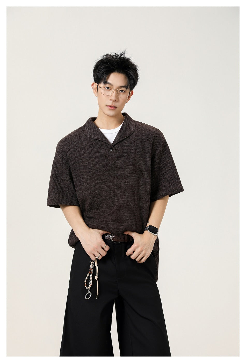 Model wearing coffee brown textured short-sleeve polo top over a white tee with black wide-leg trousers
