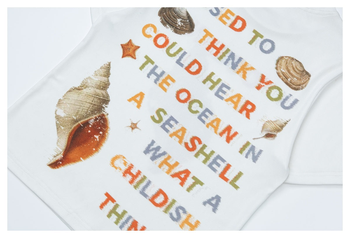 Angled close-up of a white garment with multicolored English lettering and seashell prints.
