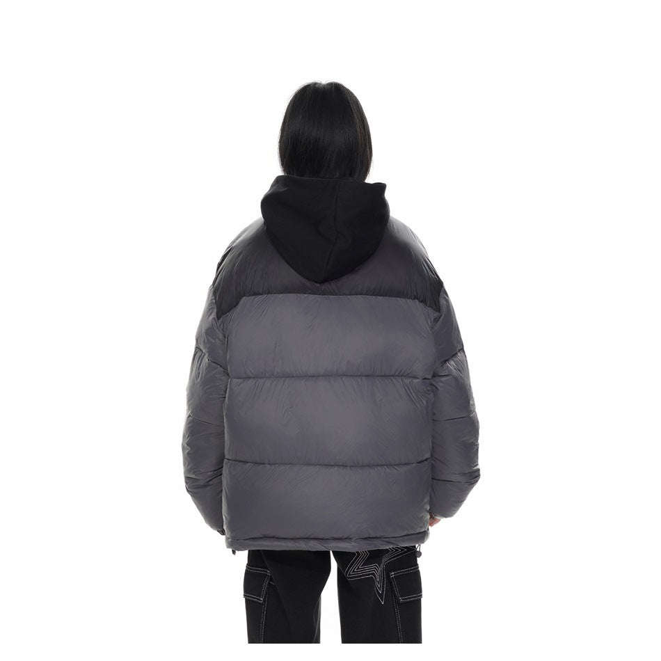 Rear view of a model wearing a charcoal-gray puffer jacket with a black shoulder panel and hood.