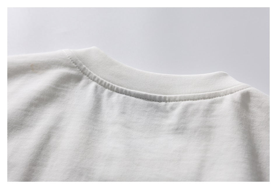 Close-up of the white garment's ribbed crew neckline and shoulder seam.