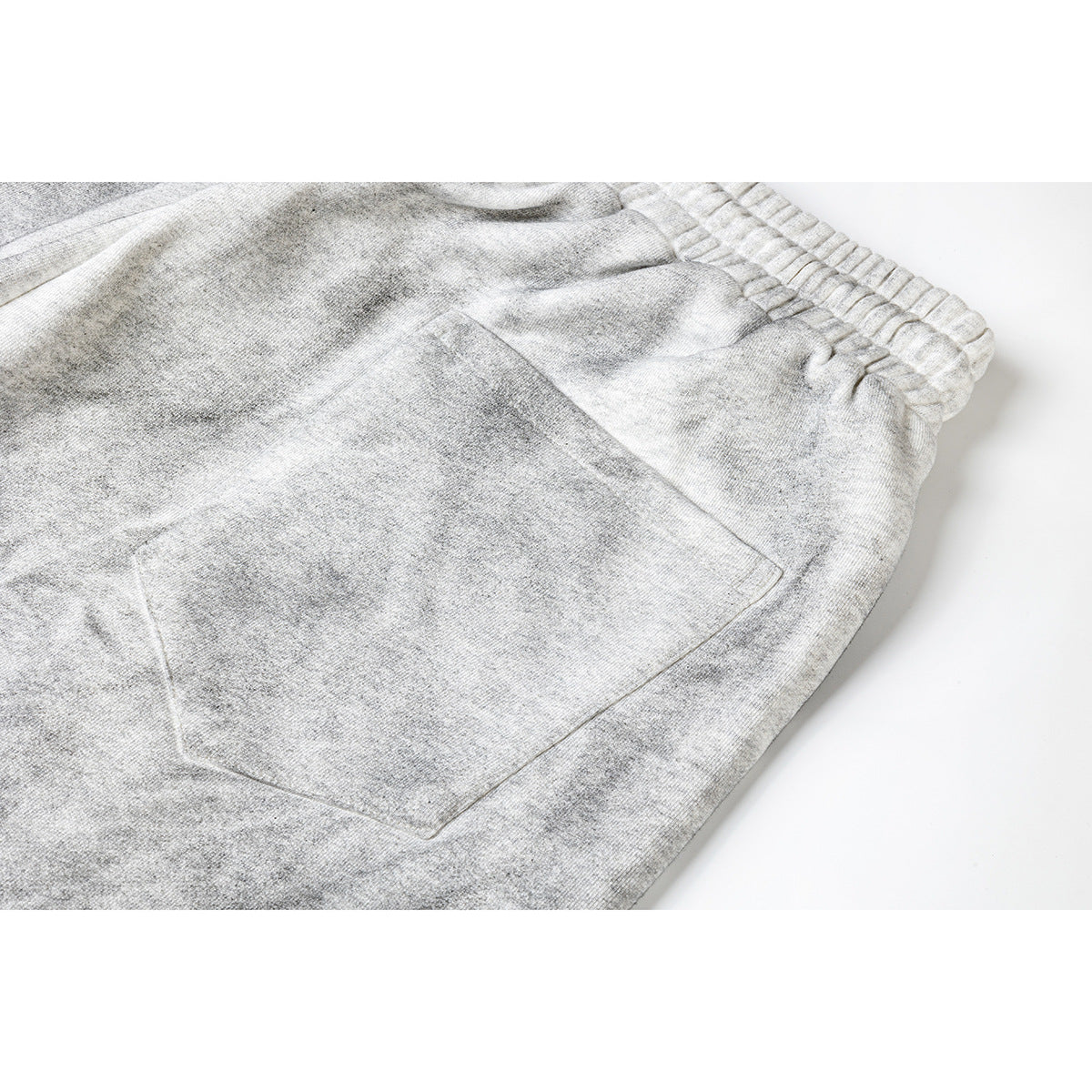 Close-up of gray athletic shorts showing a rear patch pocket and elastic waistband.
