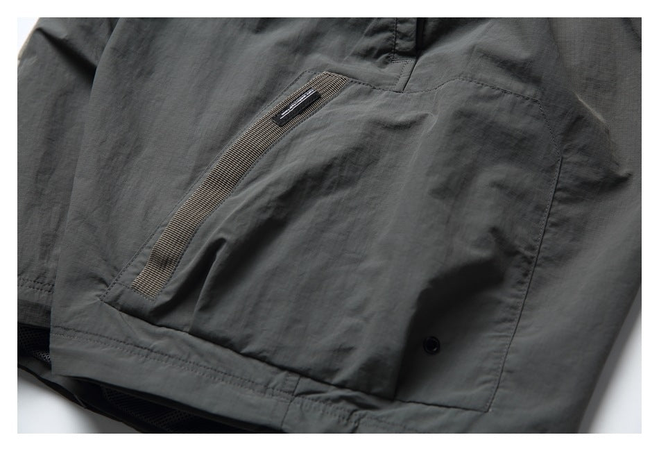 Close-up of a large pocket on a dark charcoal garment with woven trim and a snap.