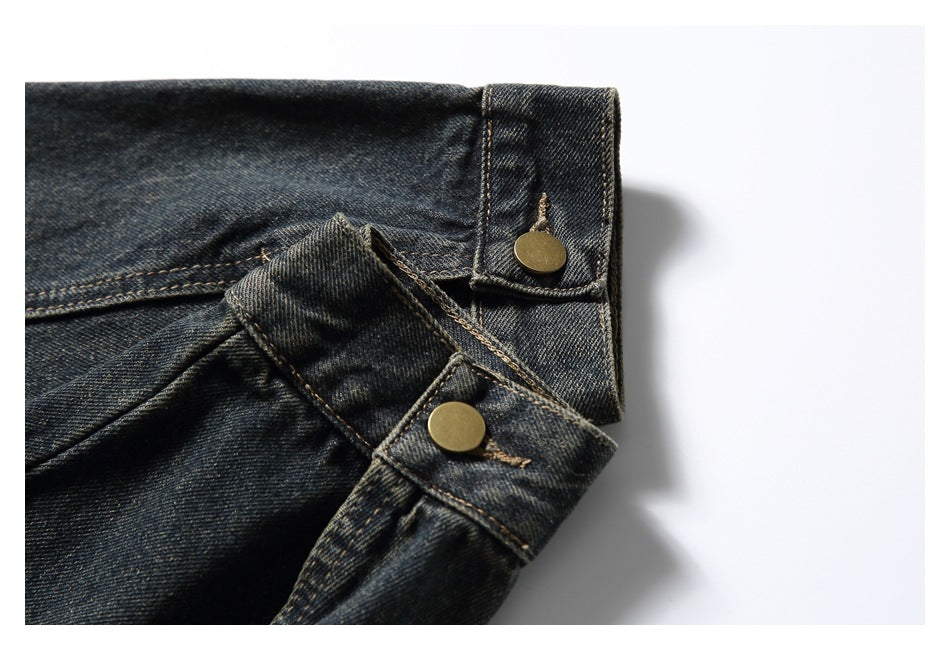 Close-up of dark indigo denim waistband with two brass-tone buttons and tan stitching.