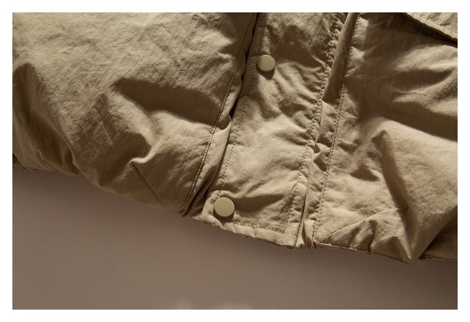 Close-up of a tan jacket's snap-button front placket, stitching, and lower hem.