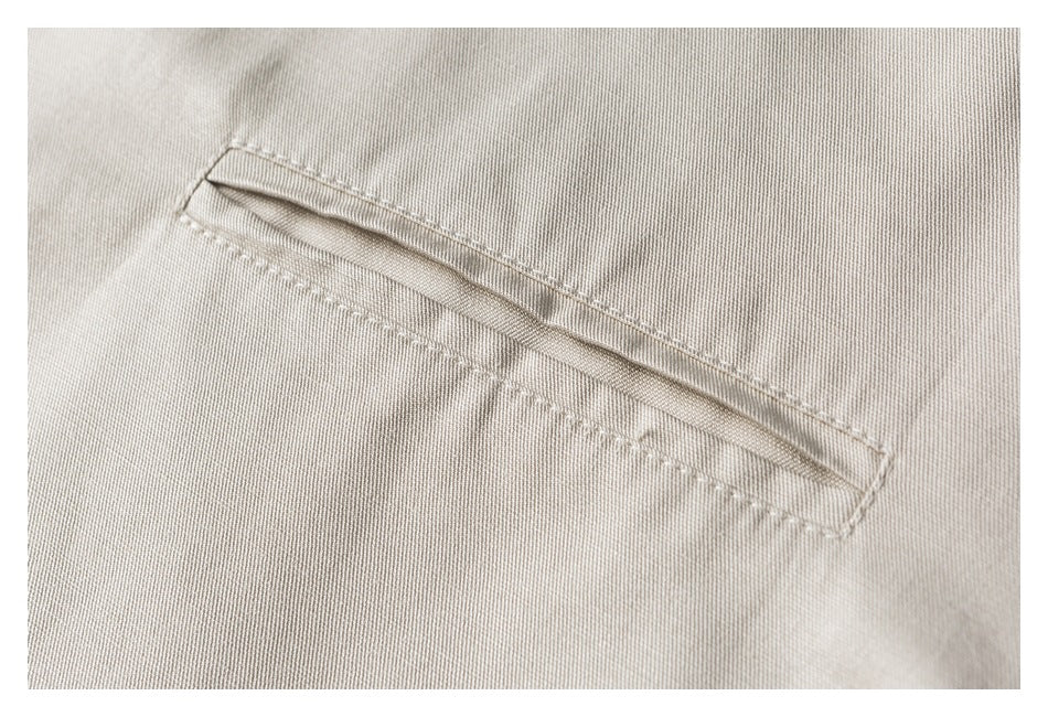 Close-up of the narrow welt chest pocket and stitching on the ivory jacket.