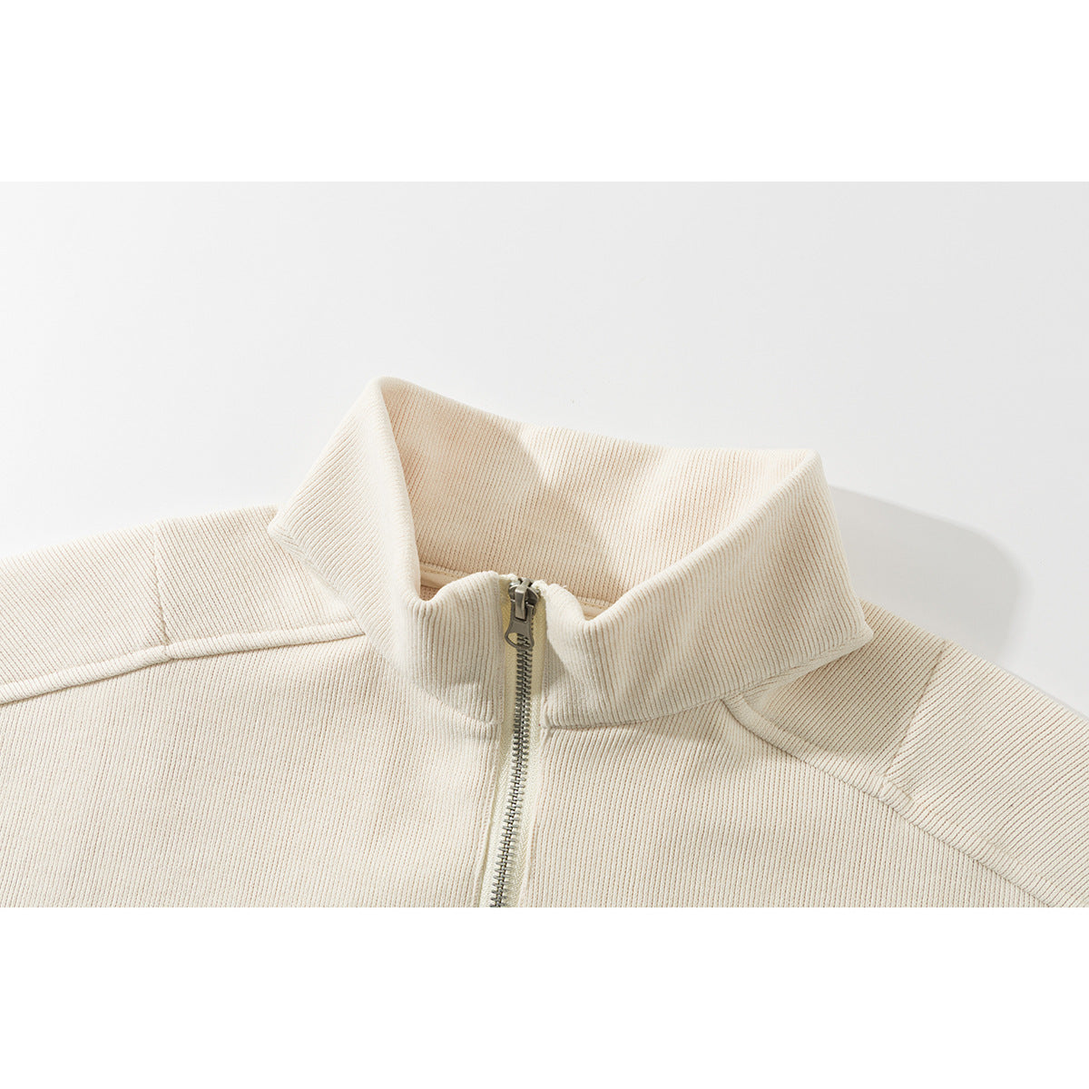 Close-up of an ivory ribbed jacket's stand collar and short front zipper.