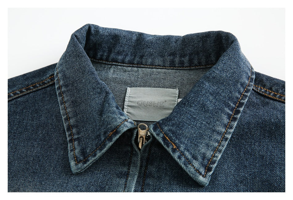 Close-up of a dark blue denim jacket collar, zipper, and gray sewn-in brand label.