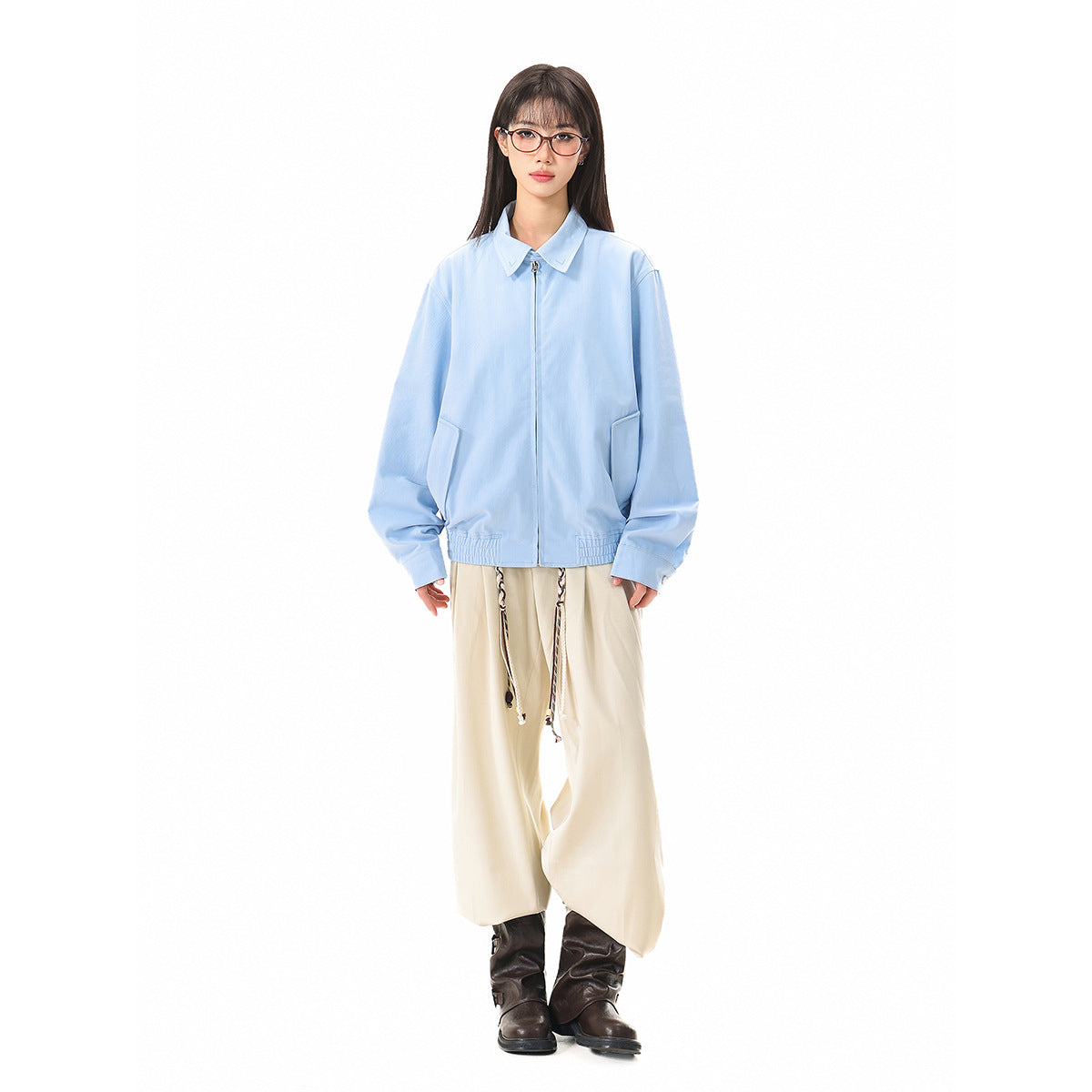 Full-length model wearing a light blue collared zip jacket with front pockets and an elastic hem, paired with cream trousers.