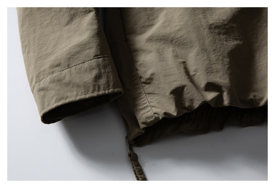 Close-up of an olive-brown jacket hem, sleeve cuff, and hanging adjustment strap.