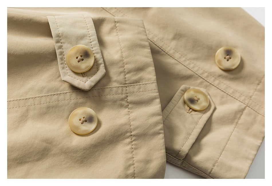 Close-up of tan coat fabric, stitched button tabs, and several round buttons.