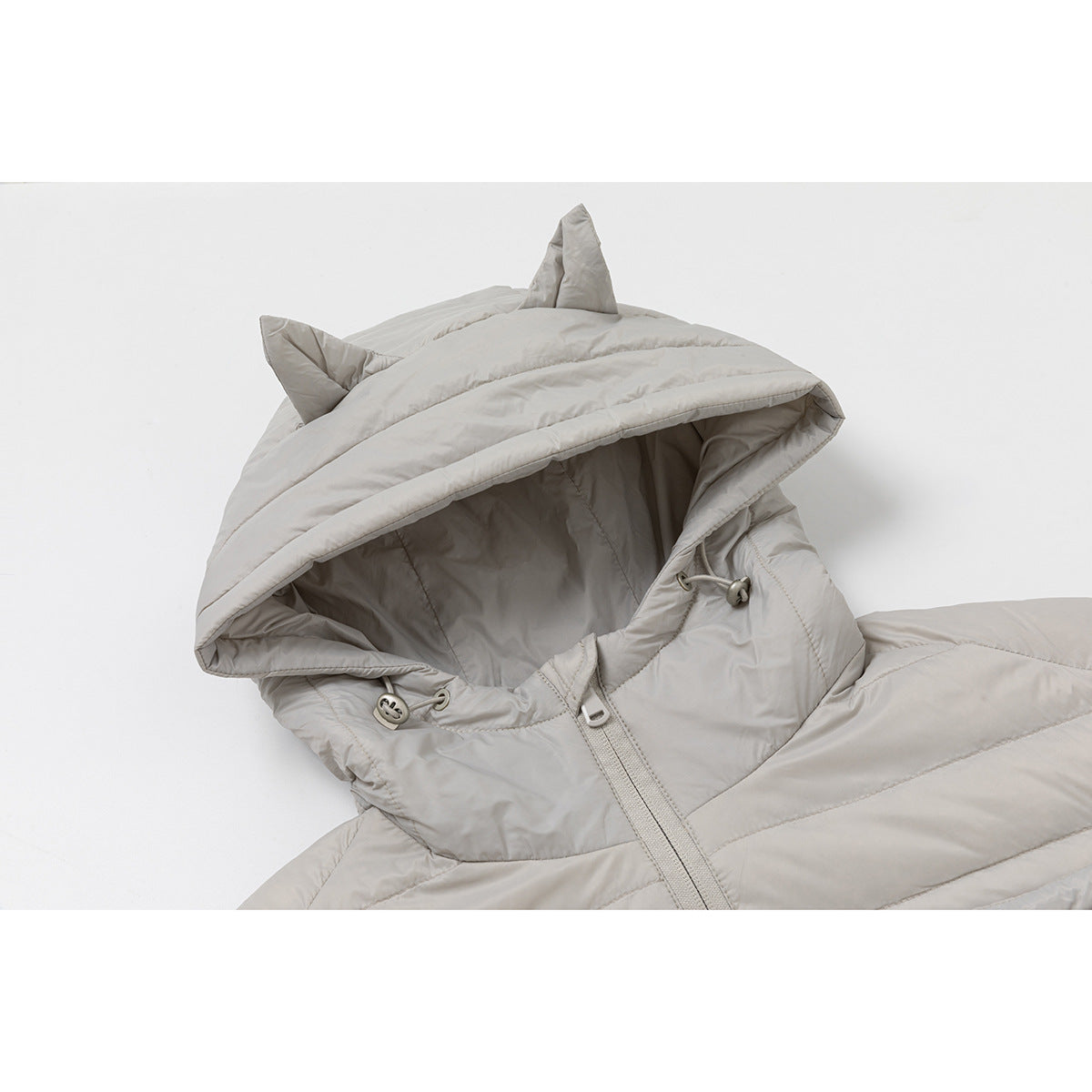 Close-up of a light gray quilted jacket with a cat-ear hood, drawcord toggles, and front zipper.