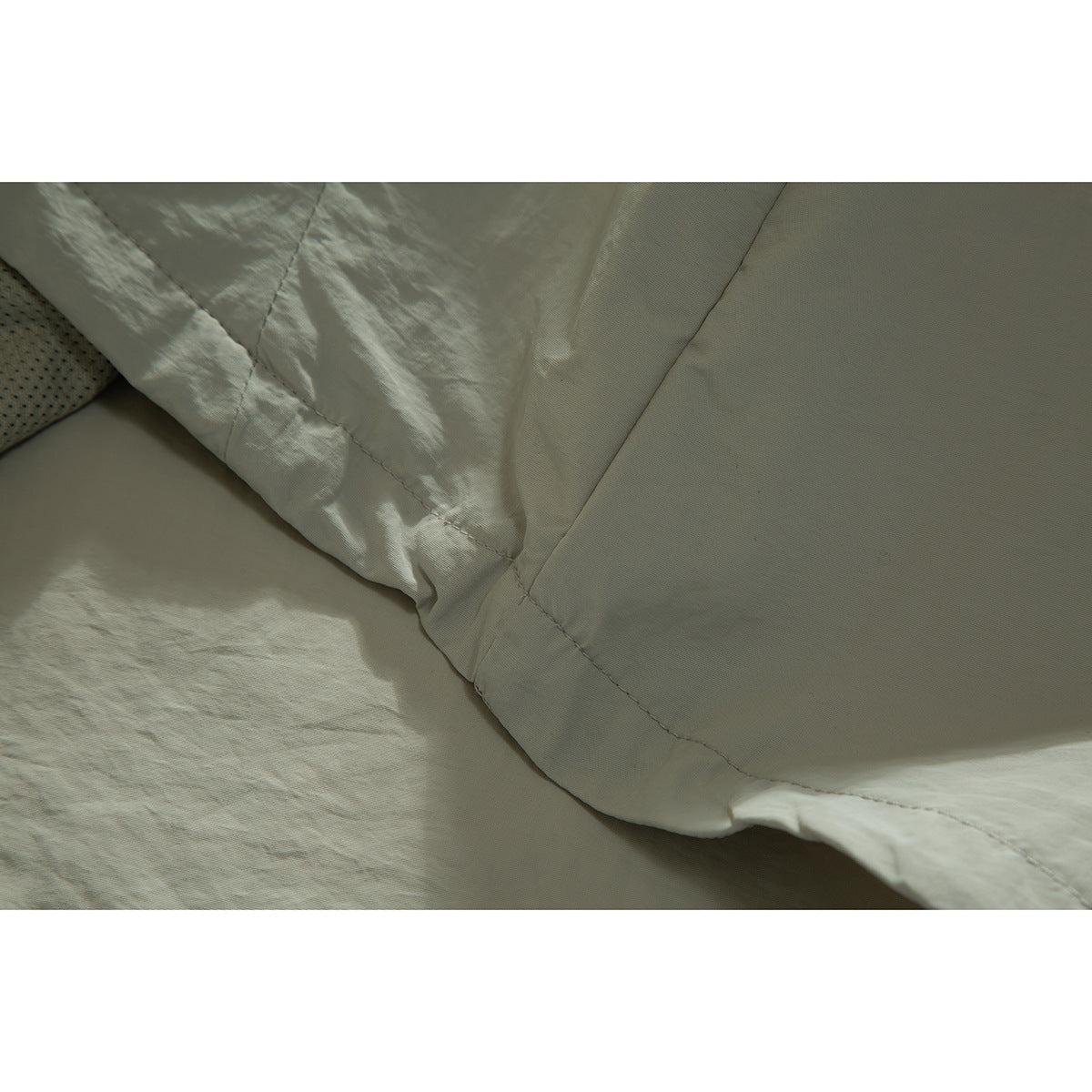 Close-up of the pale sage jacket's interior lining, seam stitching and edge finish.