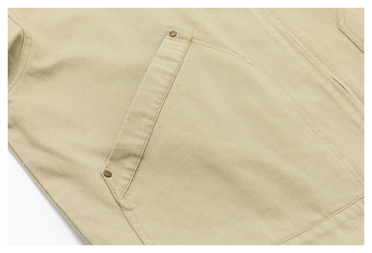 Close-up of a large square jacket pocket with a narrow snap-fastened flap on sand-beige fabric.