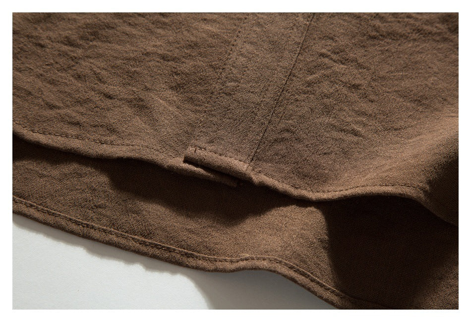 Close-up of brown garment fabric showing a folded seam and small stitched tab.