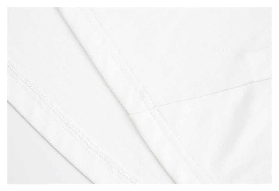 Close-up of white garment fabric with intersecting stitched seams.