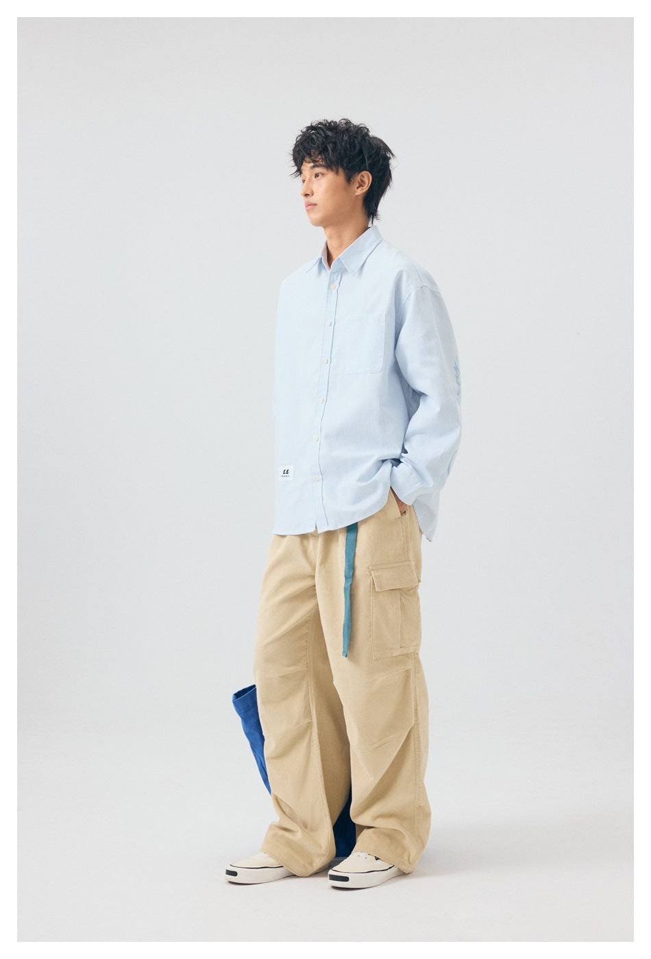 Side view of model wearing light blue striped shirt with khaki cargo pants and white sneakers