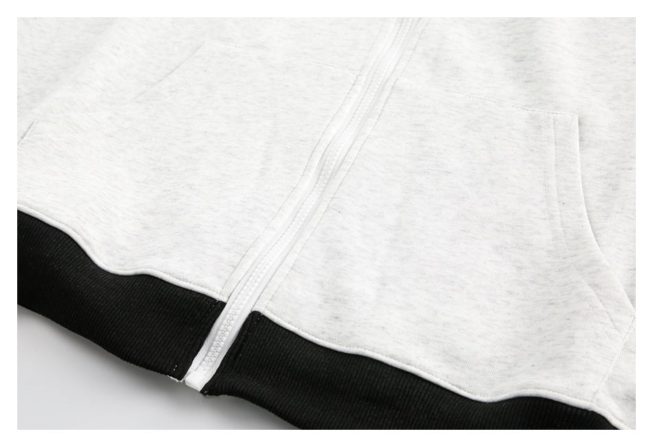 Close-up of a heather-gray zip-up sweatshirt with a front pocket and black ribbed hem.