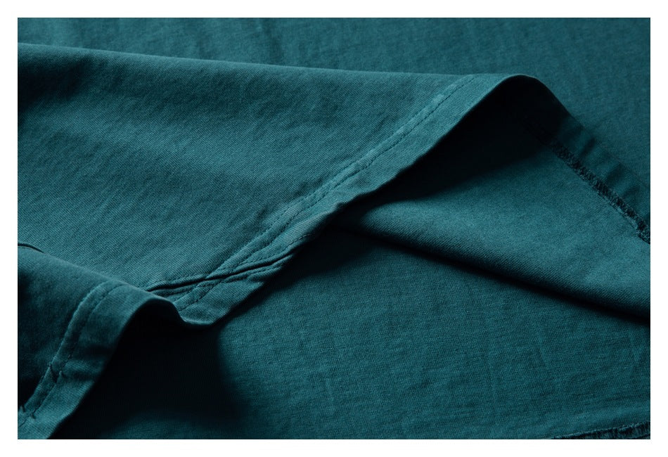 Close-up of a dark teal garment's folded edge and stitching.