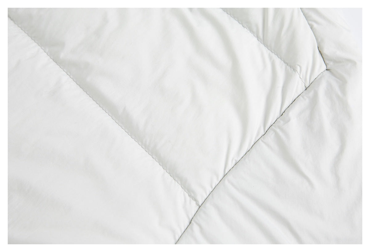 Close-up of pale gray padded fabric with intersecting stitched panel seams.