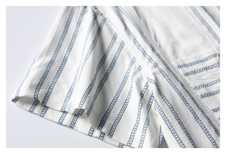 Close-up of the short sleeve and side of a white shirt with narrow blue patterned stripes.