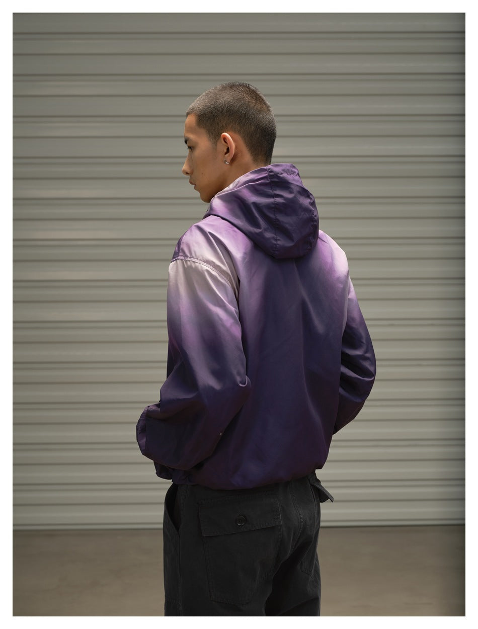 Rear view of a model wearing a purple hooded jacket with a color-blocked shoulder and sleeve detail.