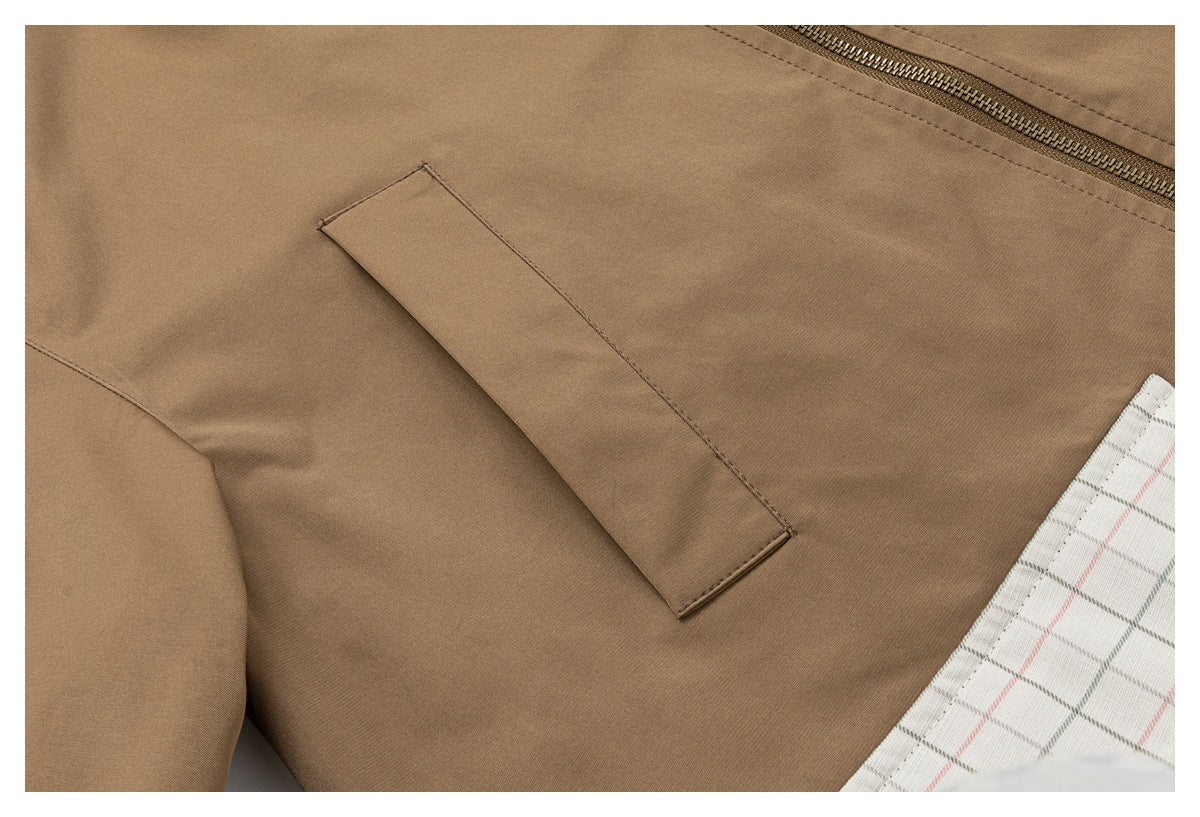 Close-up of a tan jacket seam and narrow welt pocket beside a zipper.