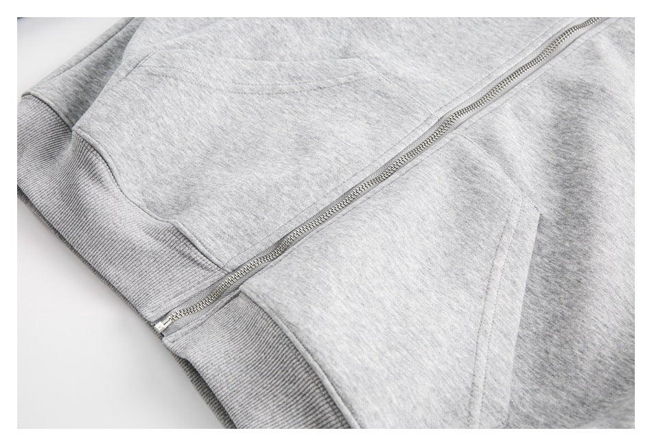 Close-up of the light gray zip hoodie’s front pocket, metal zipper, and ribbed hem.