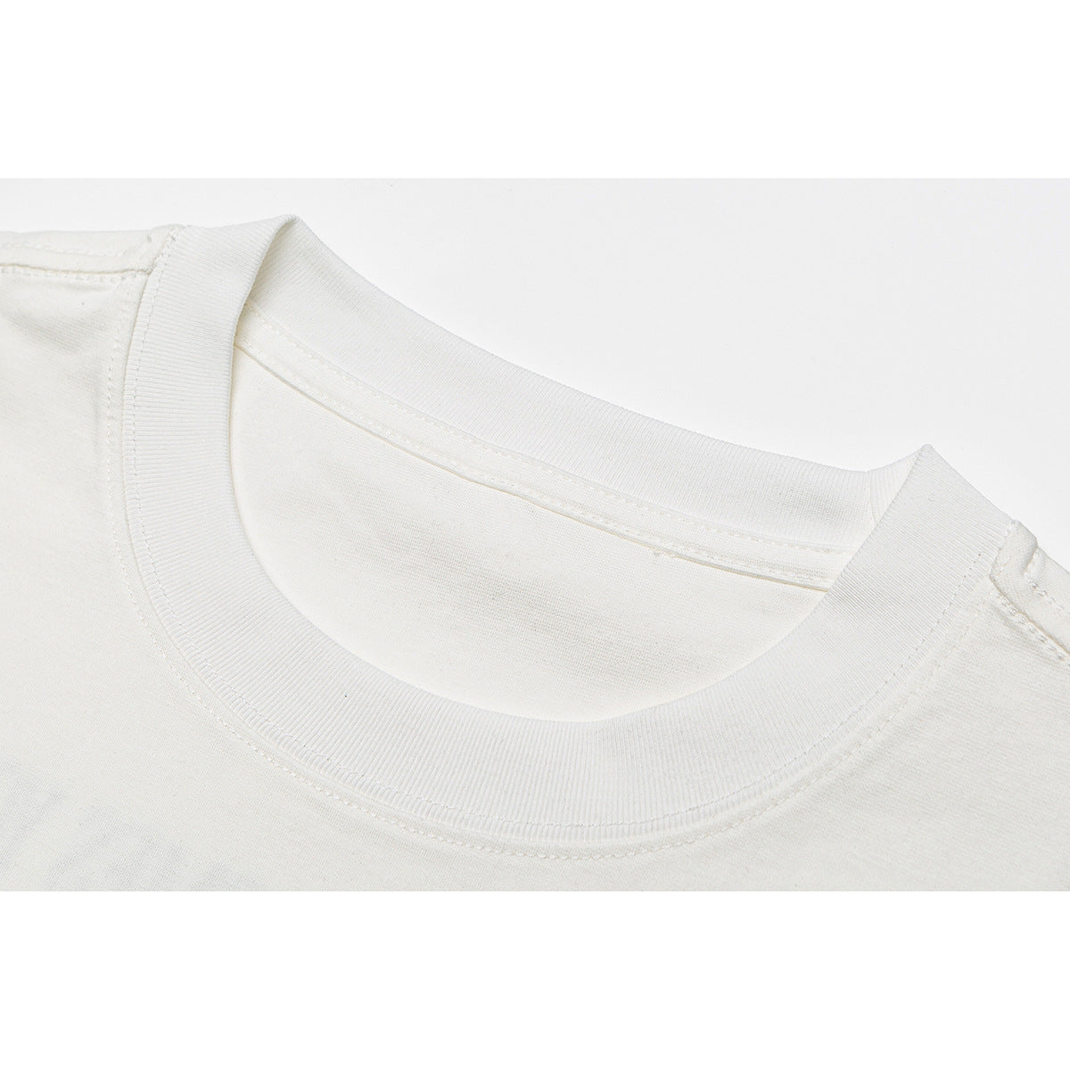 Close-up of the ribbed crew neckline and shoulder seam of an off-white T-shirt.