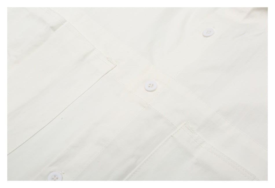 Close-up of the off-white shirt front placket, white buttons, and stitching.