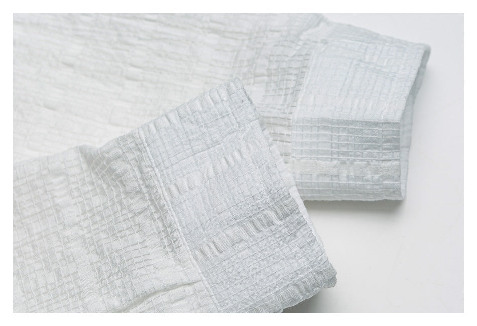 Close-up of the white textured shirt's folded sleeve cuffs.