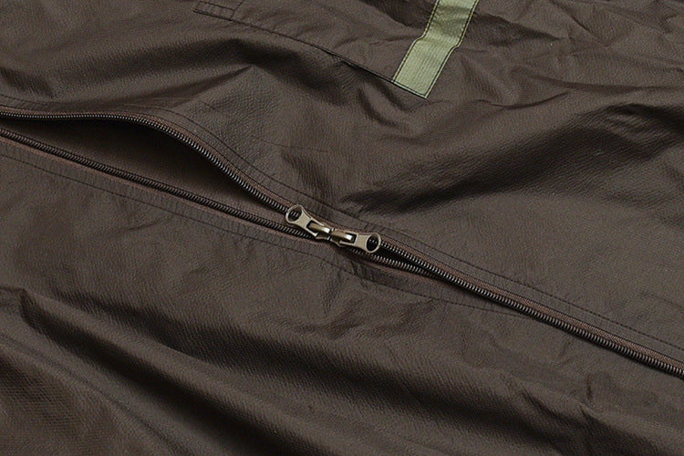 Close-up of a dark garment with a diagonal zipper and a narrow yellow-green tab.