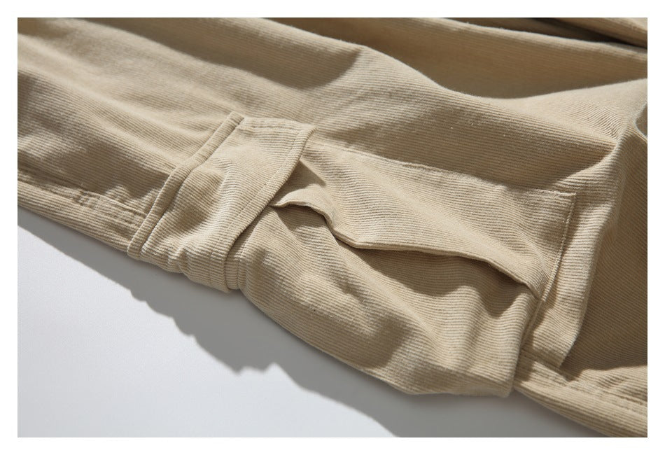 Close-up of a stitched flap pocket on tan ribbed trousers.