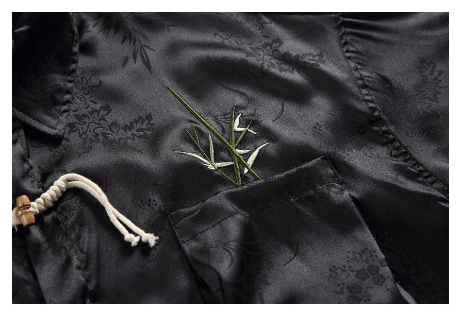Close-up of black patterned shirt fabric with green bamboo embroidery and a patch pocket.