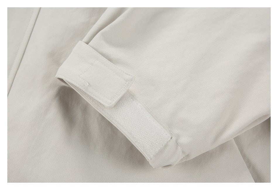 Close-up of a pale beige garment sleeve tab with a rectangular hook-and-loop fastening.