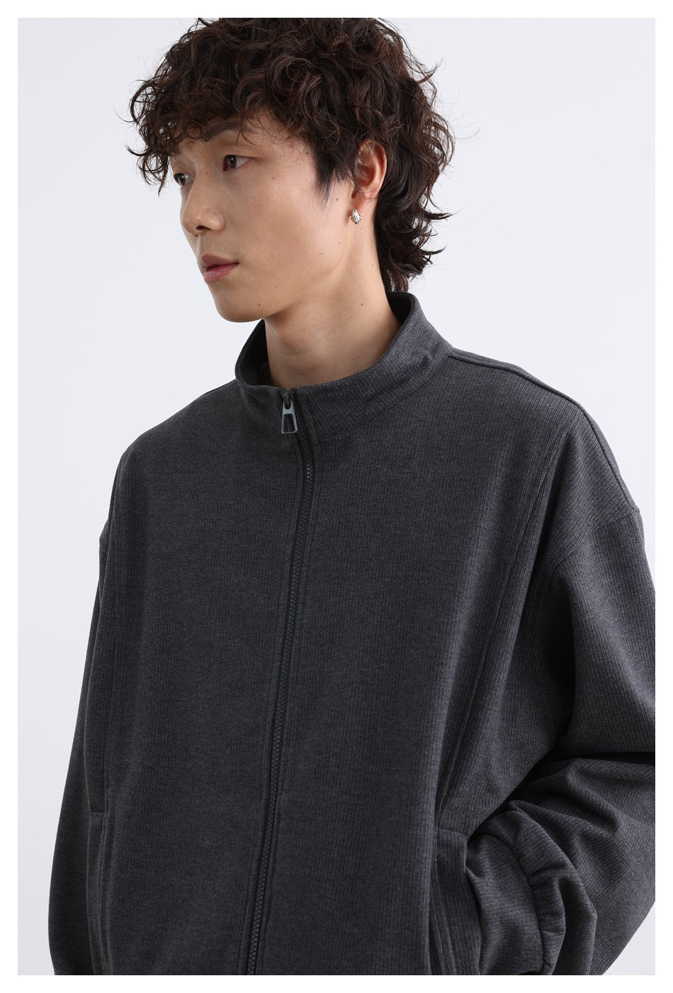 Model wearing dark gray zip jacket, close-up of stand collar and front zipper