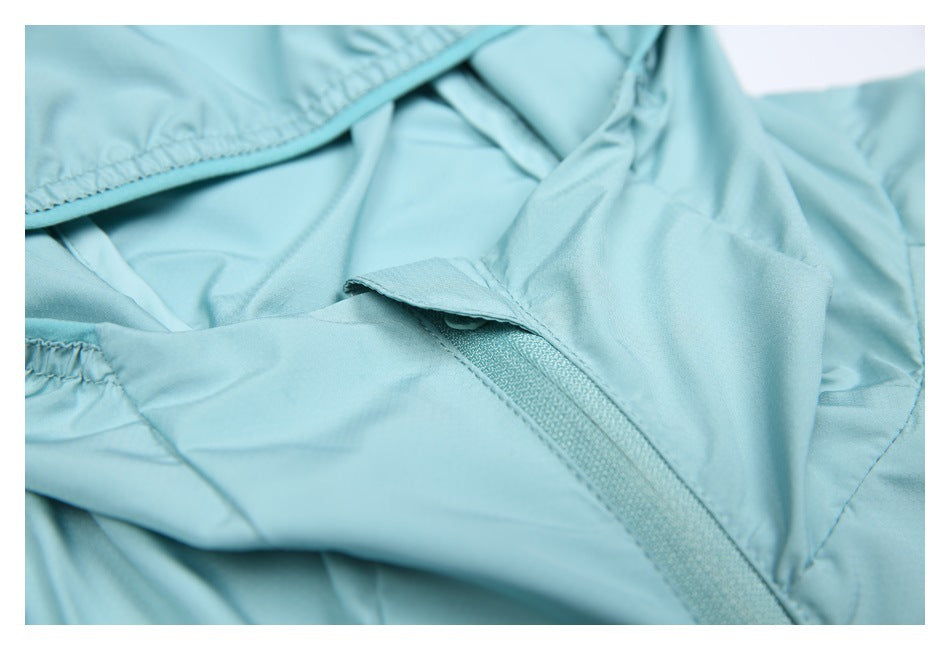 Close-up of a light aqua jacket's zipper beneath a small fabric flap near the hood.