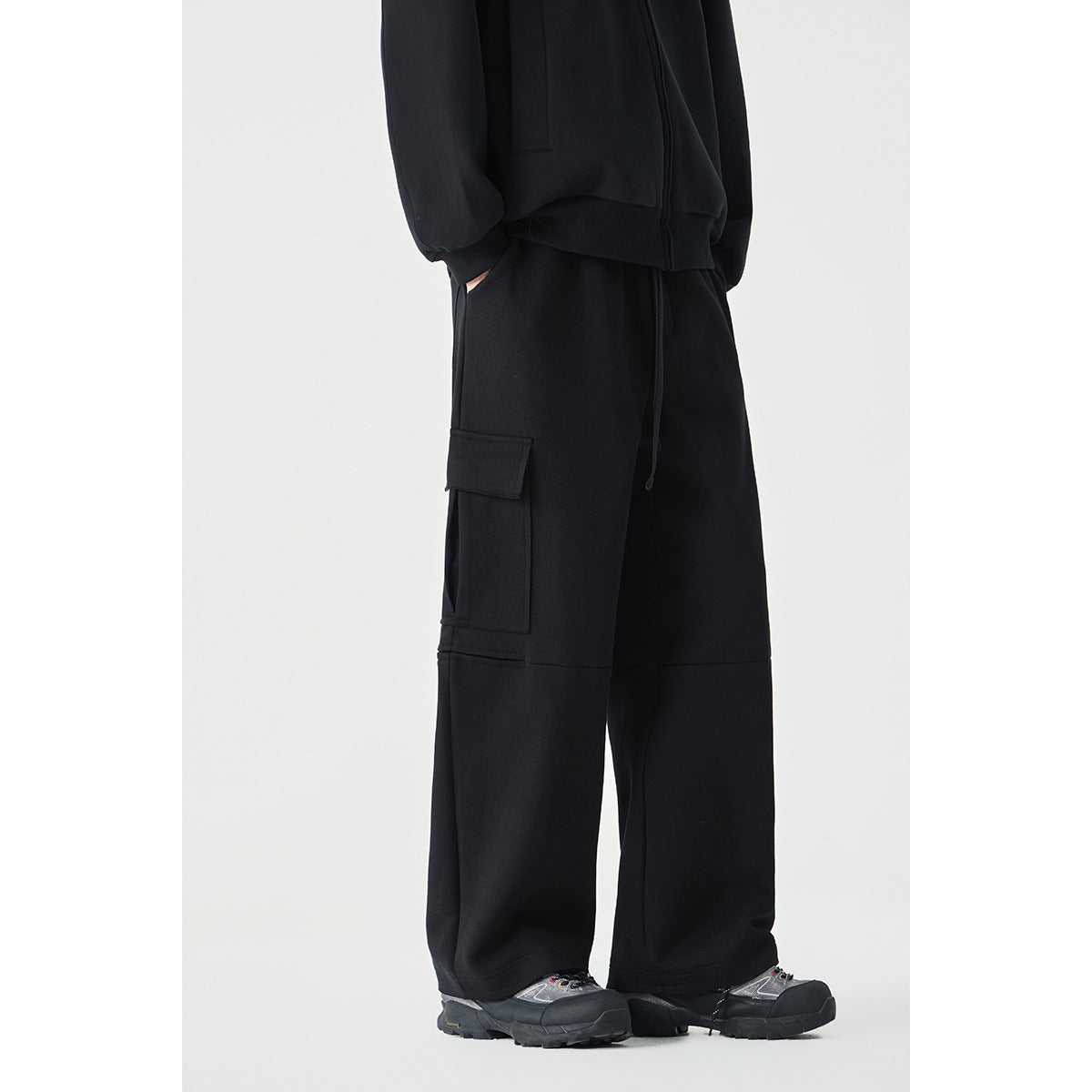Model wearing black wide-leg cargo pants with a flap side pocket, shown from the waist down at an angle.
