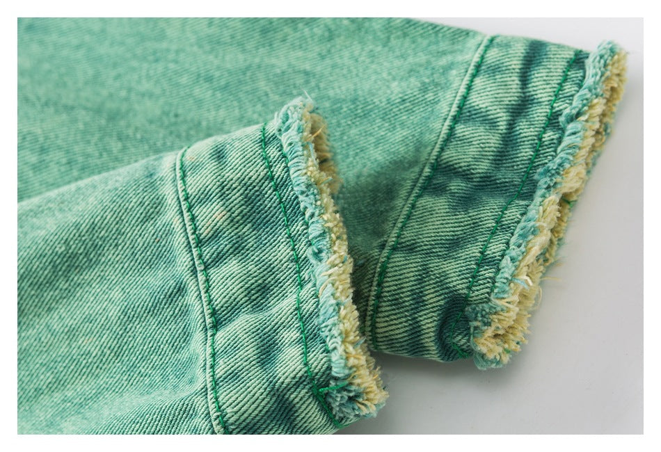 Close-up of a teal denim cuff with yellow-and-teal frayed edging and visible stitching.