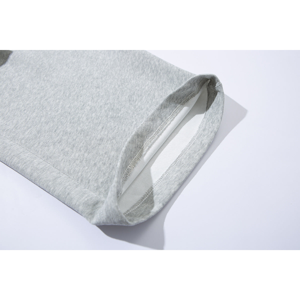 Close-up of the stitched hem on light gray heather sweatpants.