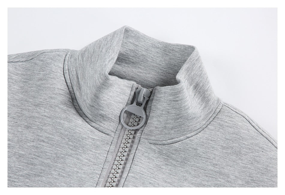 Close-up of a light gray jacket's stand collar and chunky front zipper with a round pull.