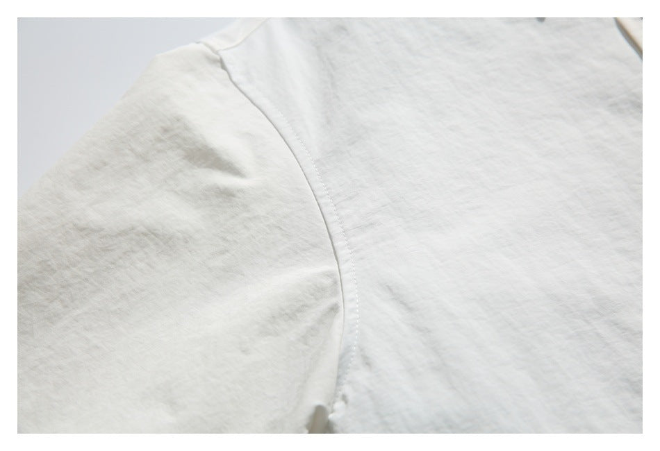 Close-up of the off-white shirt's shoulder seam and lightly textured fabric.