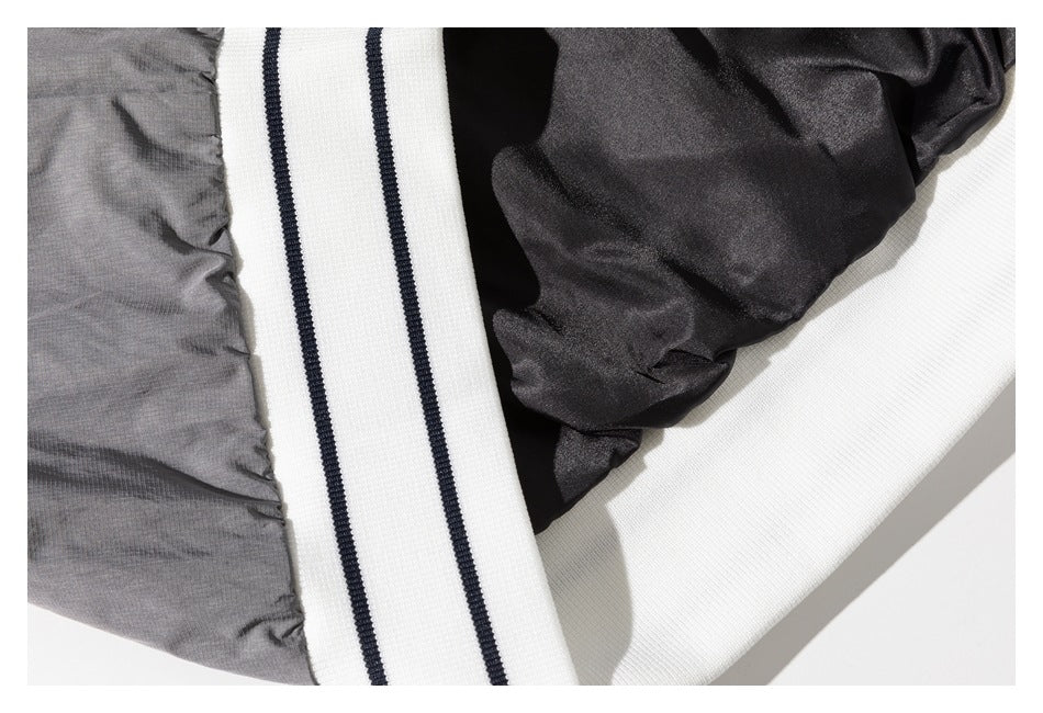 Close-up of gray jacket fabric, dark lining, and a white ribbed edge with dark stripes.