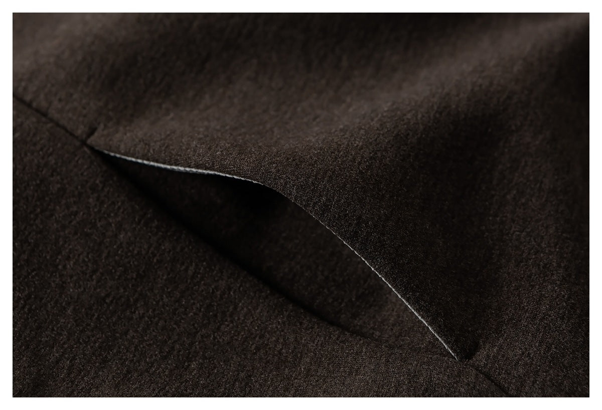 Close-up of a dark brown coat’s overlapping fabric panel and seam.