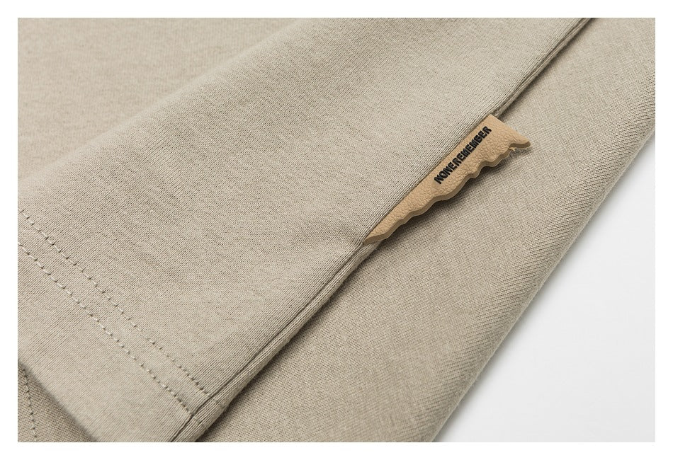 Beige garment close-up with stitched seams and a small tan fabric label.