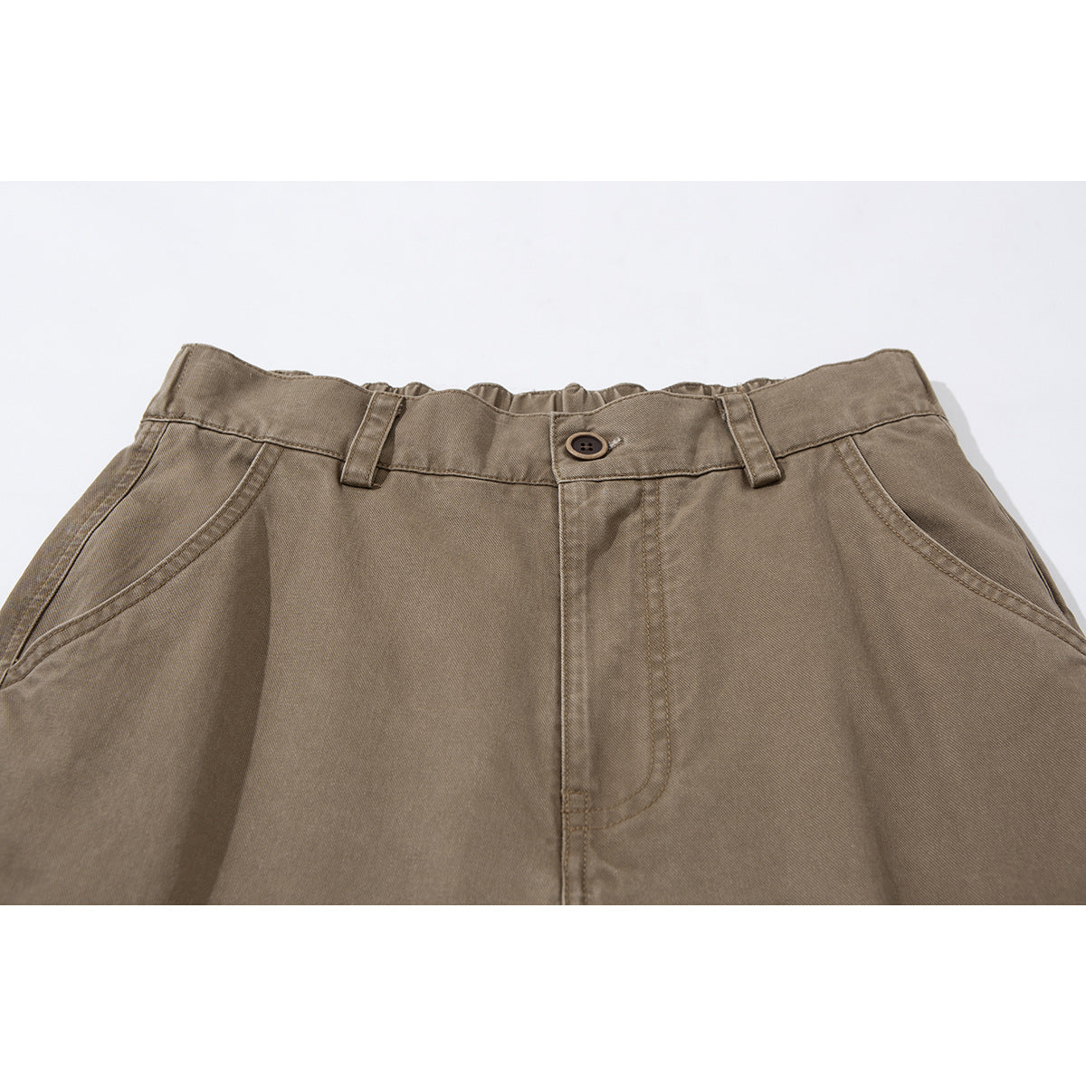 Close-up of taupe cargo trousers showing the buttoned waistband, belt loops, fly and curved front pockets.