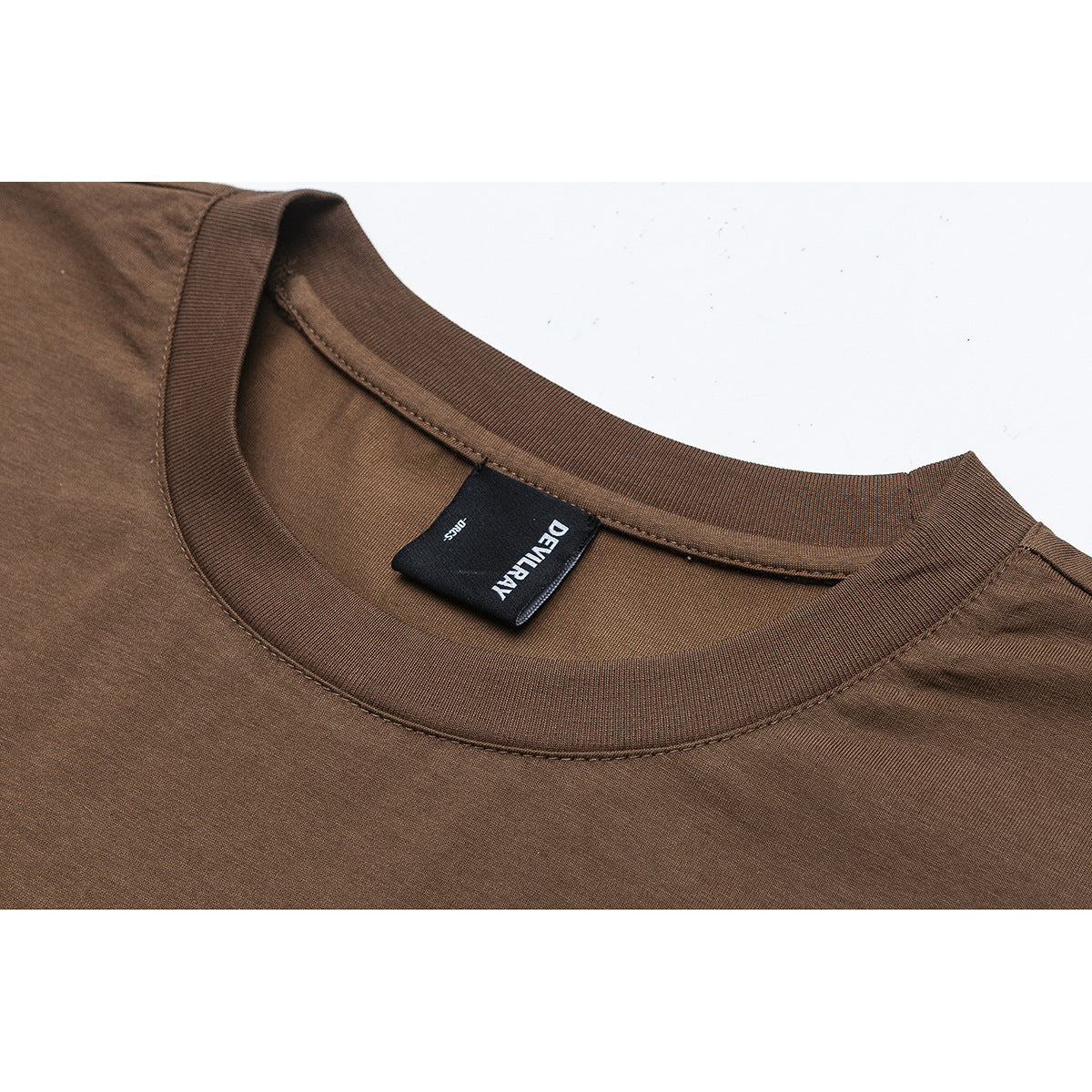 Close-up of a brown crew-neck shirt showing the ribbed collar, stitching, and sewn-in black neck label.