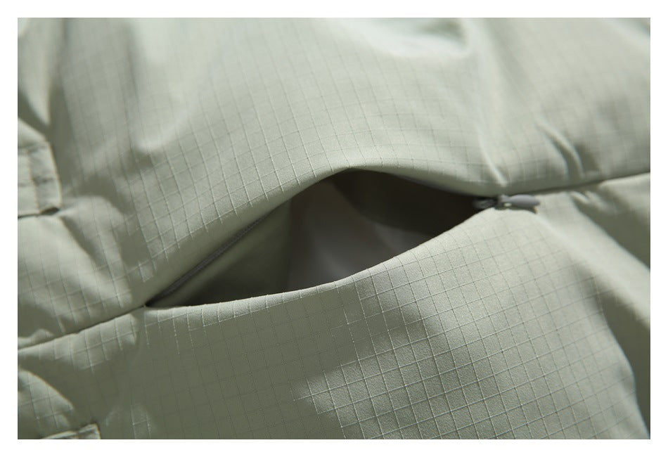 Close-up of a pale sage jacket with a slanted zippered pocket opening.